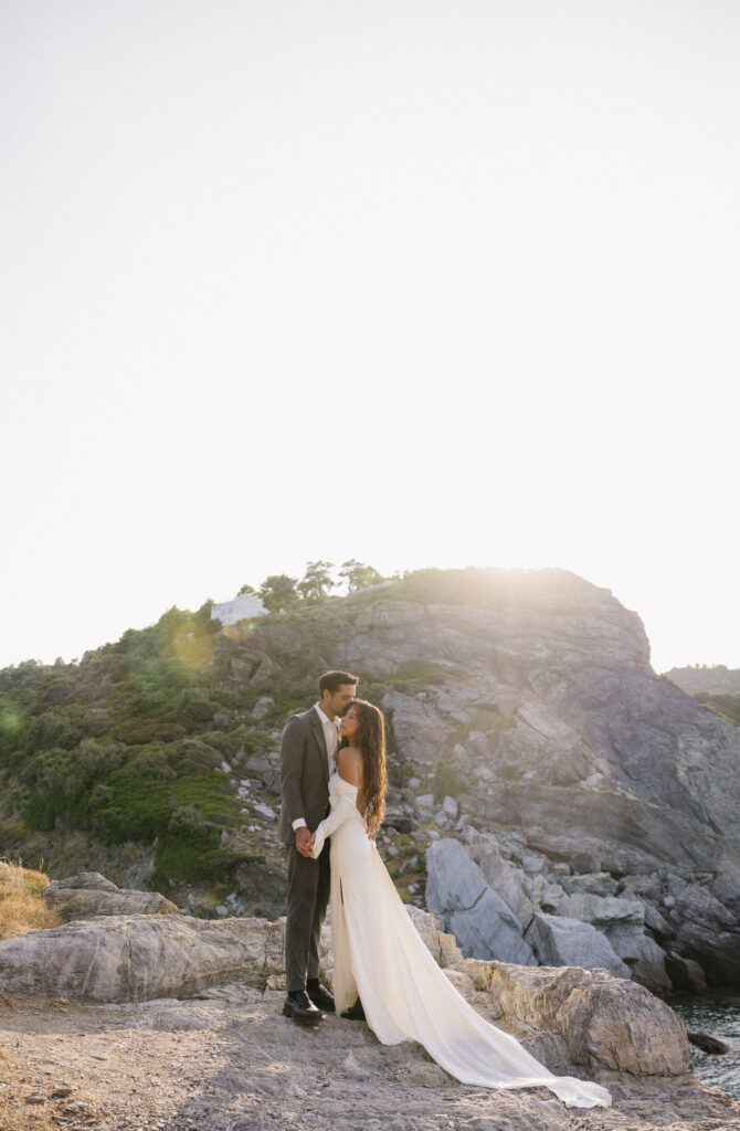 Sunset Elopement in Skopelos Greece. Couple standing on a cliffside after reading private vows.